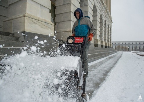 individual using snowblower on city sidewalk