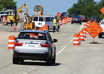 cars driving on road with construction workers